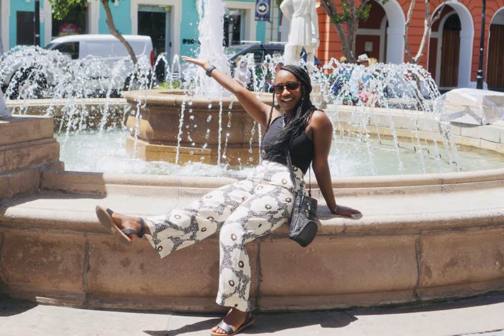 Woman sitting on the fountain in la plaza de armas in old san juan
